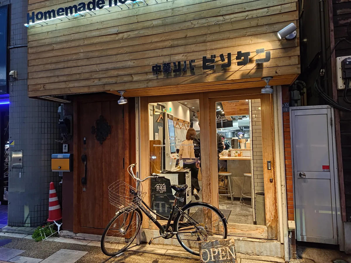 Außenansicht des Chūka Soba Billiken. Schwarzer Noren-Vorhang, Namensschild '中華ソバ ビリケン' und ein Ticketautomat neben dem Eingang sind sichtbar. Japanese ramen shop exterior in Asakusa, Tokyo, Japan.