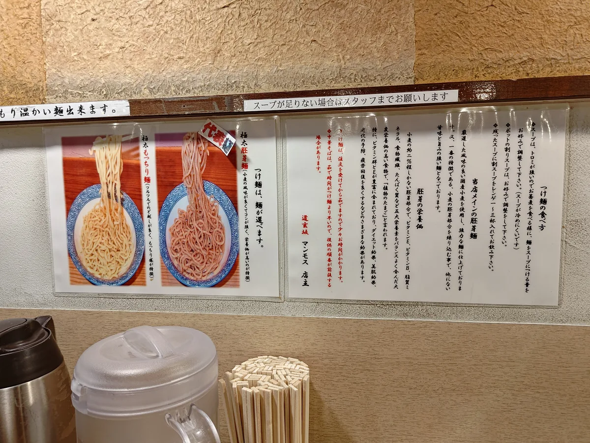 Guide on how to eat tsukemen at Dogenzaka Manmosu, a Japanese ramen shop in Shibuya. The poster explains using thick soup and warisupu (diluted soup) for a complete ramen experience in Japan, helpful for tourists.