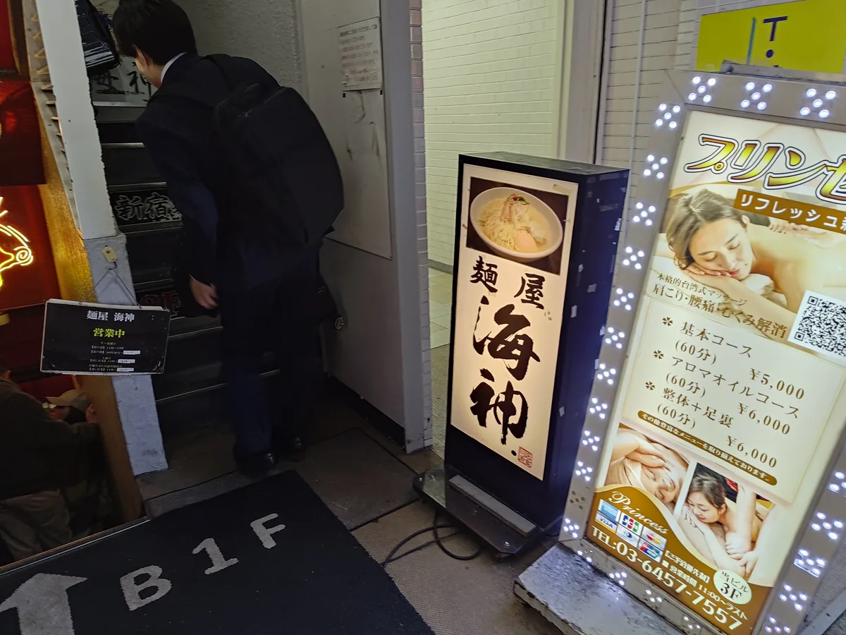 綜合大樓入口旁豎立的麵屋海神長條招牌。日本拉麵、麵屋海神、新宿美食、招牌