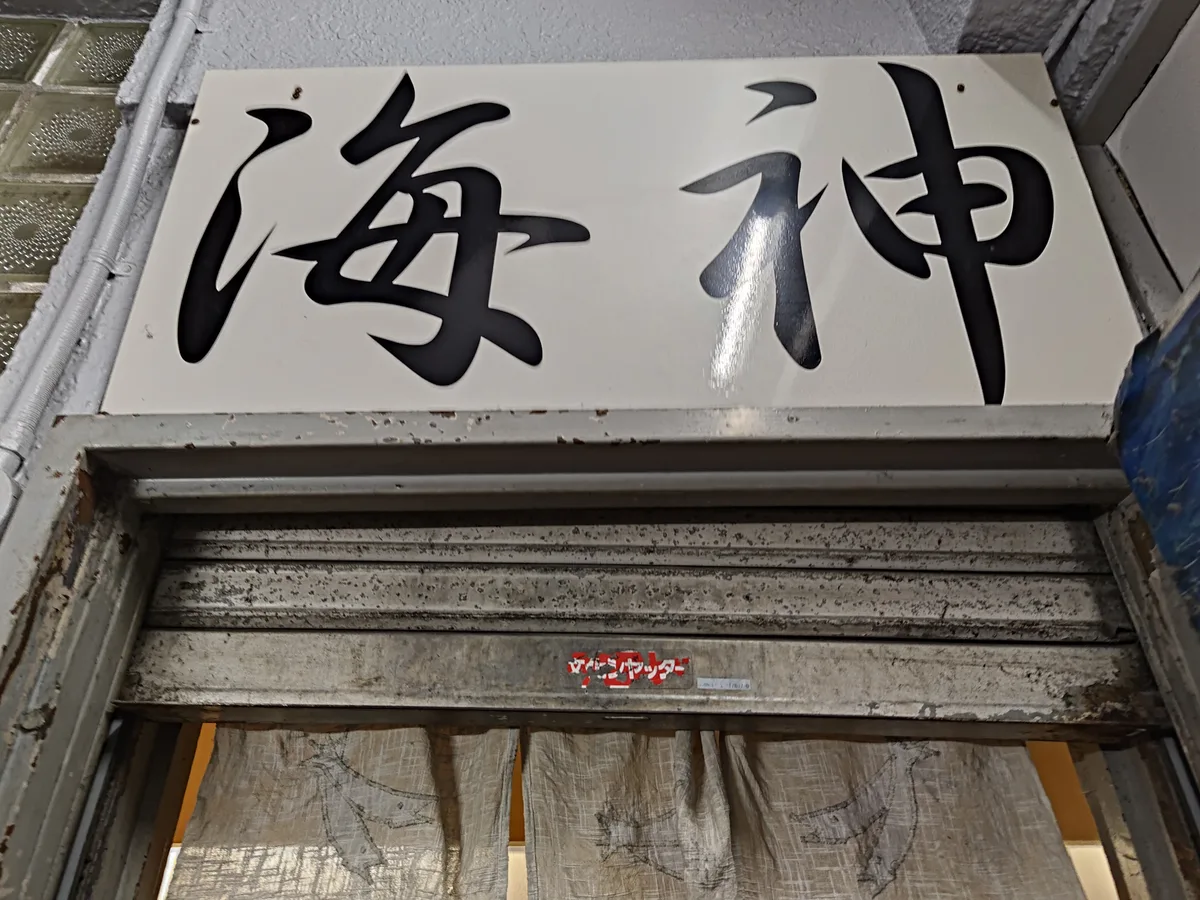 通往店家的樓梯。樓梯狹窄陡峭，頭頂可見店家招牌。日本新宿、拉麵店、內部