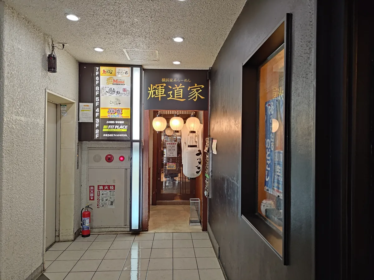 輝道家 水道橋駅前店の外観。ビルの奥まった通路に「輝道家」の看板と提灯が見える。