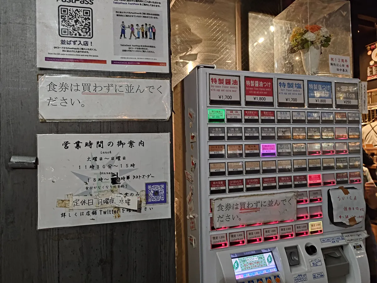 麺処ほん田の食券機全体。上段の大きなボタンが「特製」メニュー。左に「食券は買わずに並んでください」の張り紙、営業時間案内、TableCheckのQRコードがある。