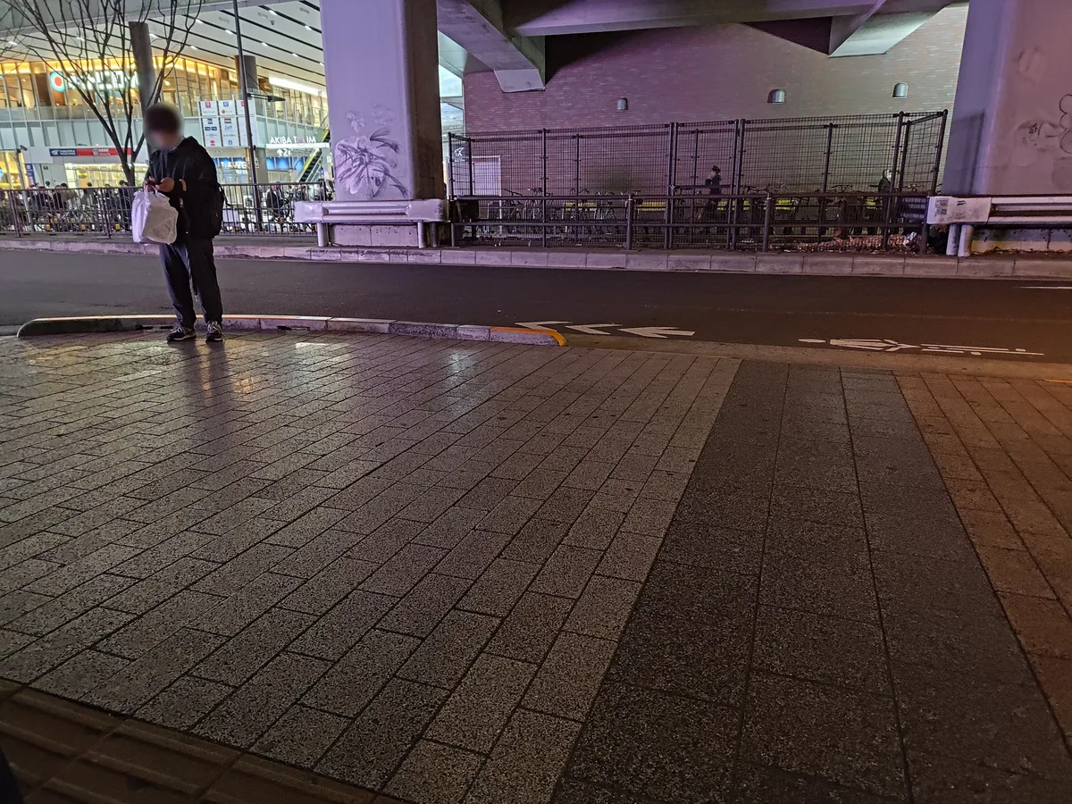 列が端に到達し、向かい側に一人で立って並んでいる様子。列と離れているため、ただ立っている人のように見える。