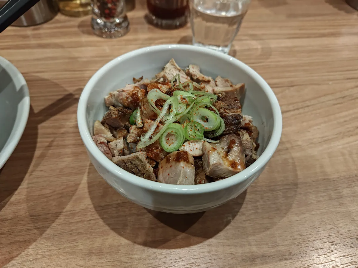 肉めし。鶏と豚のチャーシュー端肉がたっぷり盛られ、甘辛いタレとネギがかかっている。