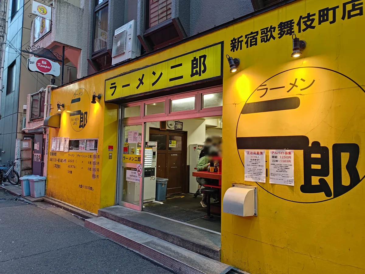 ラーメン二郎 新宿歌舞伎町店の店舗外観。「ラーメン二郎」の店名サインと黄色の看板、入口右手に券売機が見える。