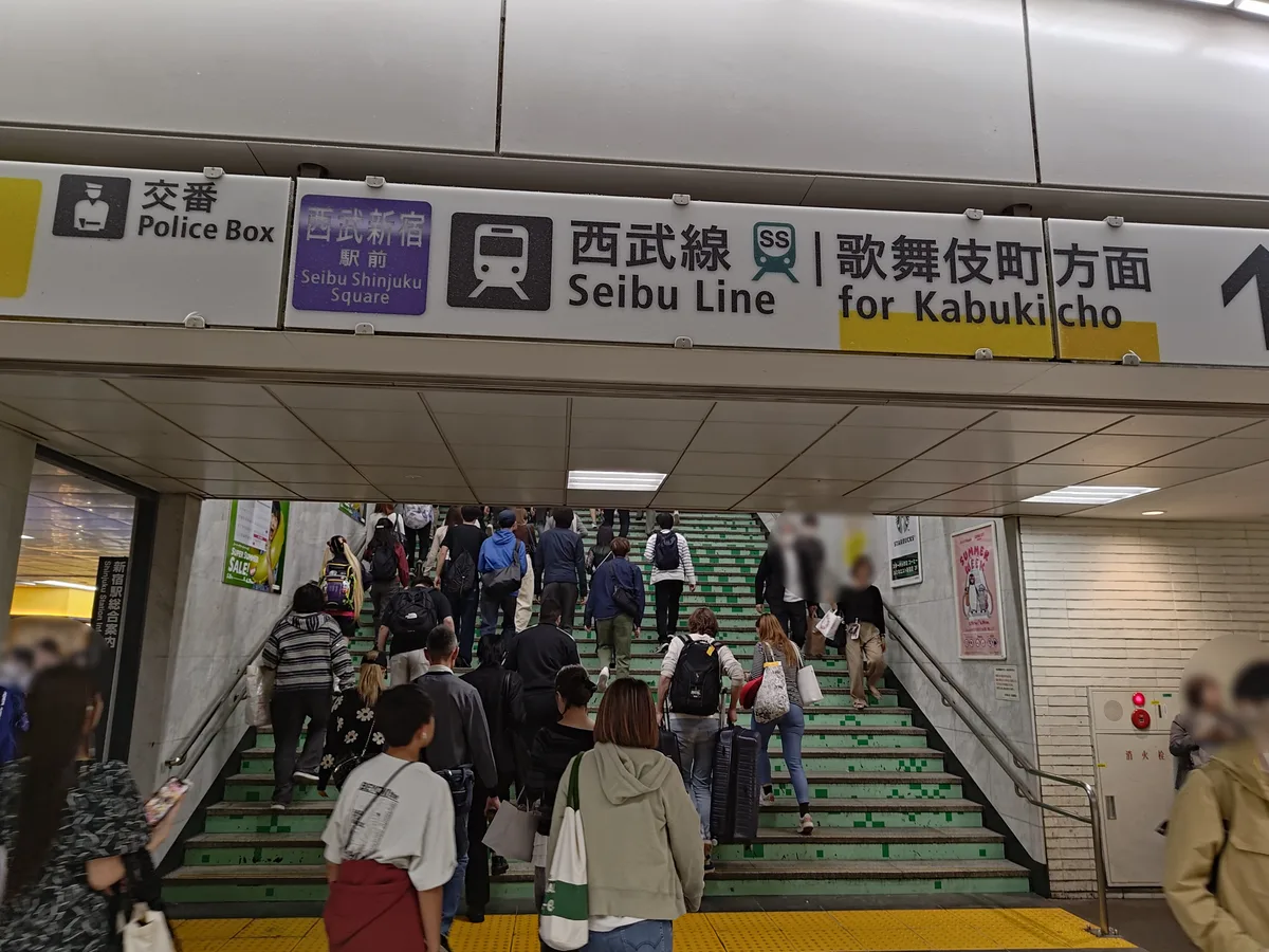 西武新宿駅北口（歌舞伎町方面）の出口。西武新宿駅の駅看板と歌舞伎町方面への案内表示が見える。