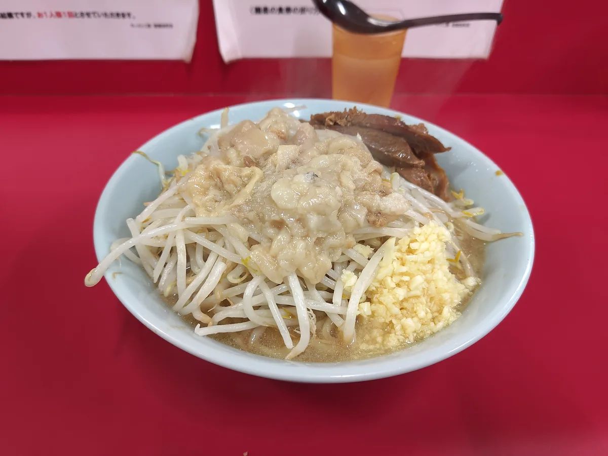 カブジのラーメン（小・コール「ニンニク少なめ・ヤサイ・アブラ」）。微乳化の豚骨醤油スープの上にヤサイ（もやし）、赤身の厚切りチャーシュー2枚、ニンニク、アブラ（背脂）が乗る。